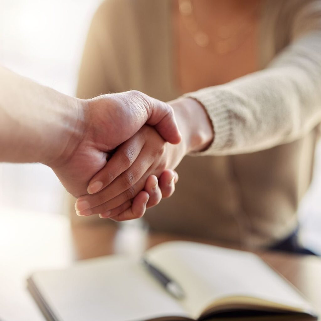 Uścisk dłoni między pracodawcą a nowym pracownikiem przy biurku – rozpoczęcie współpracy i zatrudnienia